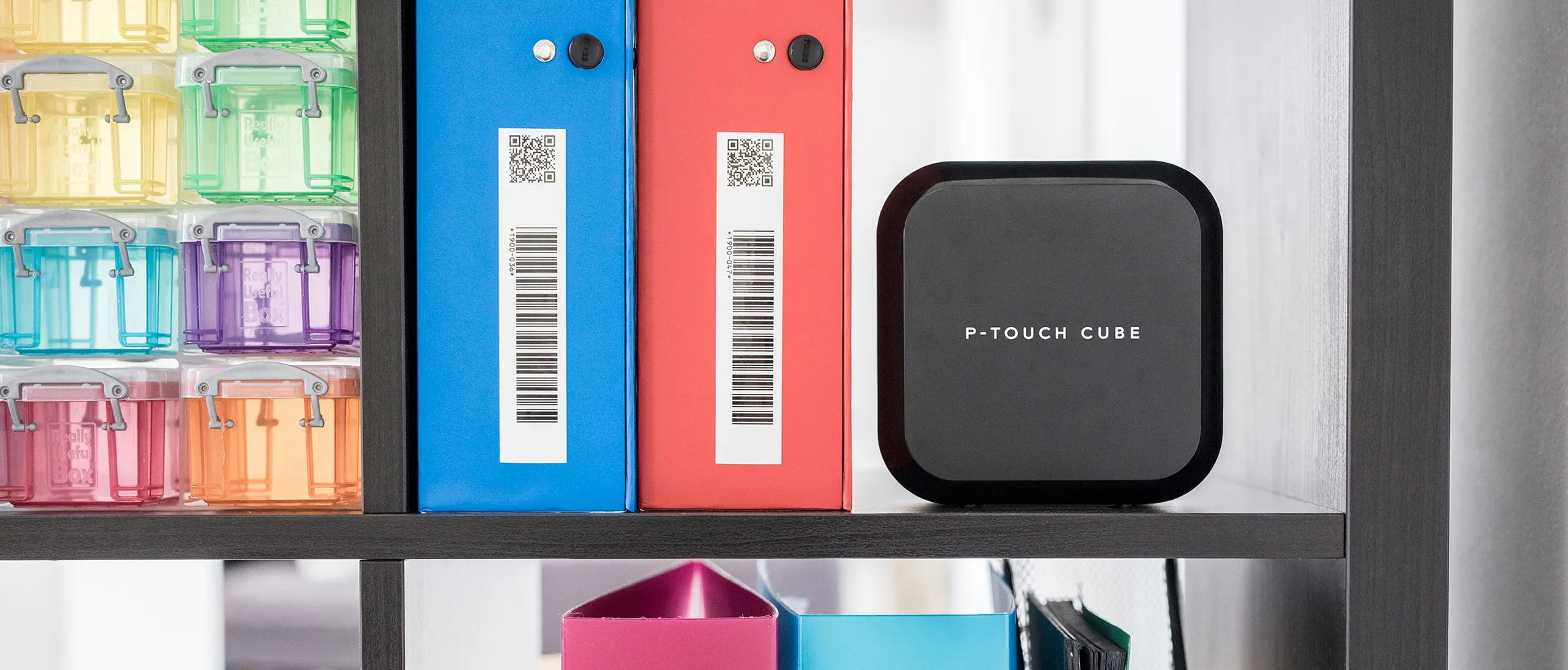 Etichettatrice Brother P-Touch Cube Plus su uno scaffale con raccoglitori etichettati